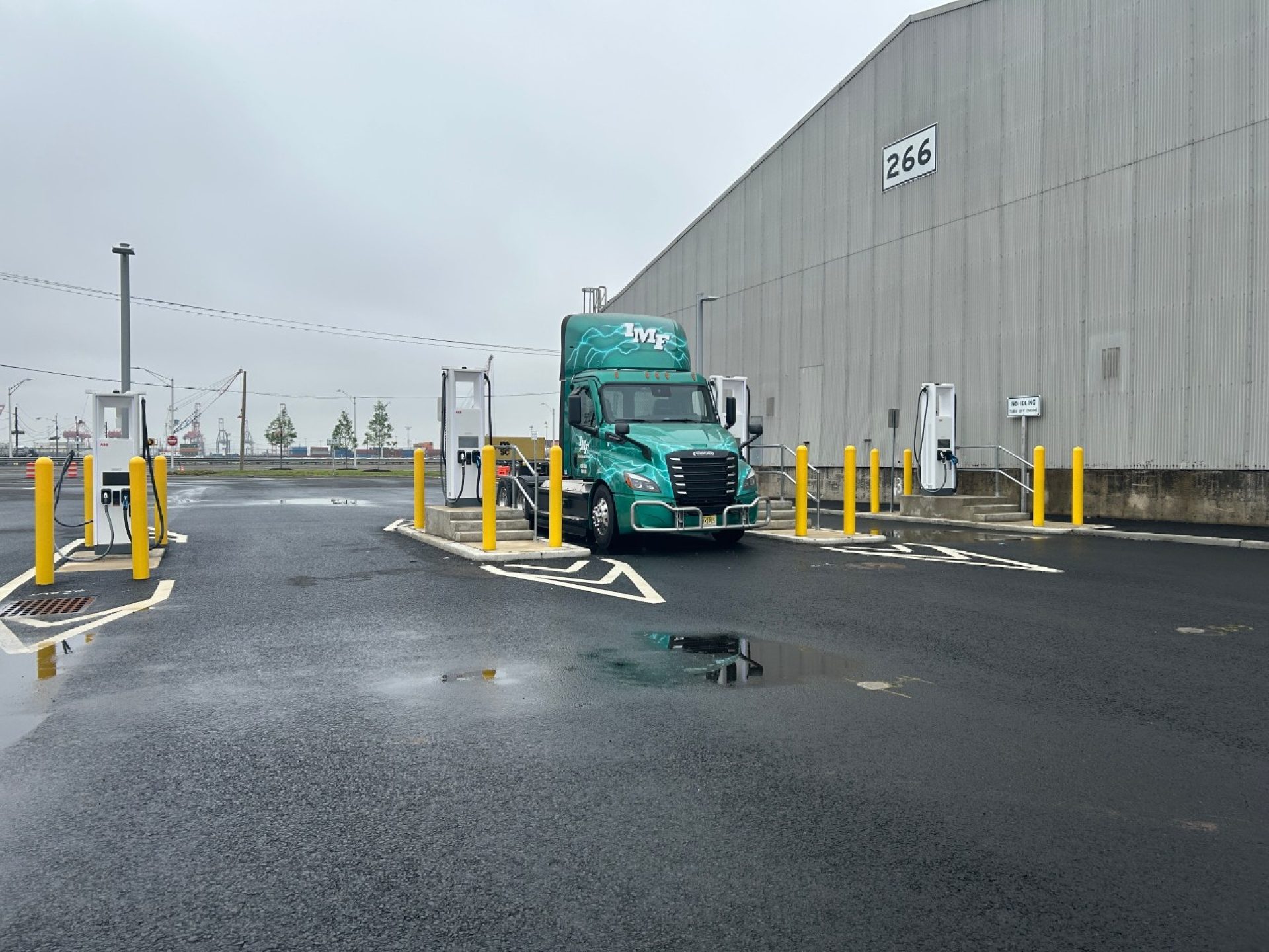 Zero-emission trucks at a port terminal with shipping containers in the background